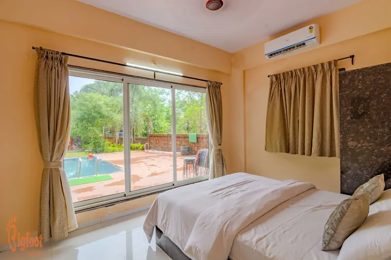 Bedroom at Hideaway Villa with a garden-facing window and dark wood wardrobe