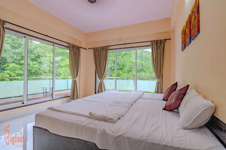 Bedroom with a large garden-facing window at Hideaway Villa