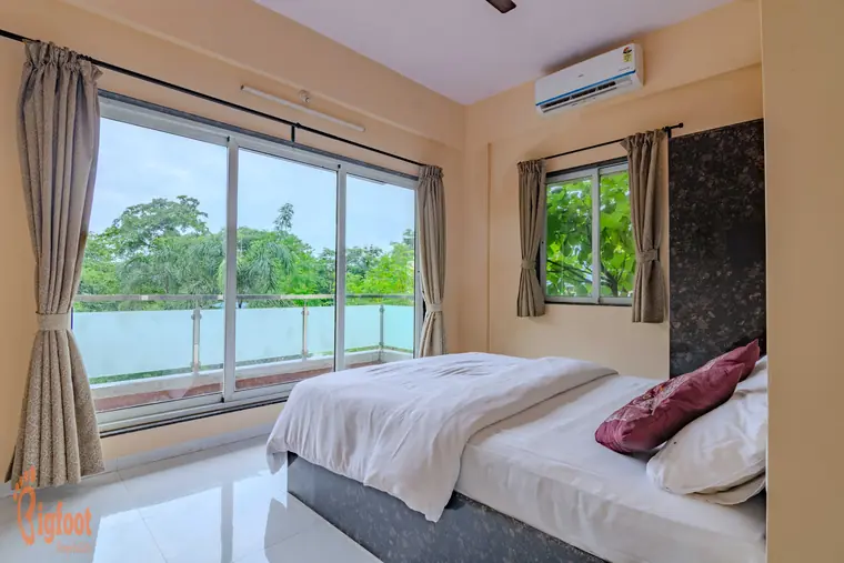 Bright bedroom at Hideaway Villa with twin windows overlooking greenery